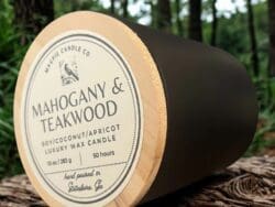 Mahogany and teakwood candle on wood surface.
