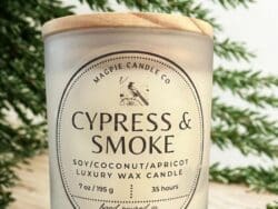Candle labeled "Cypress & Smoke" with greenery.