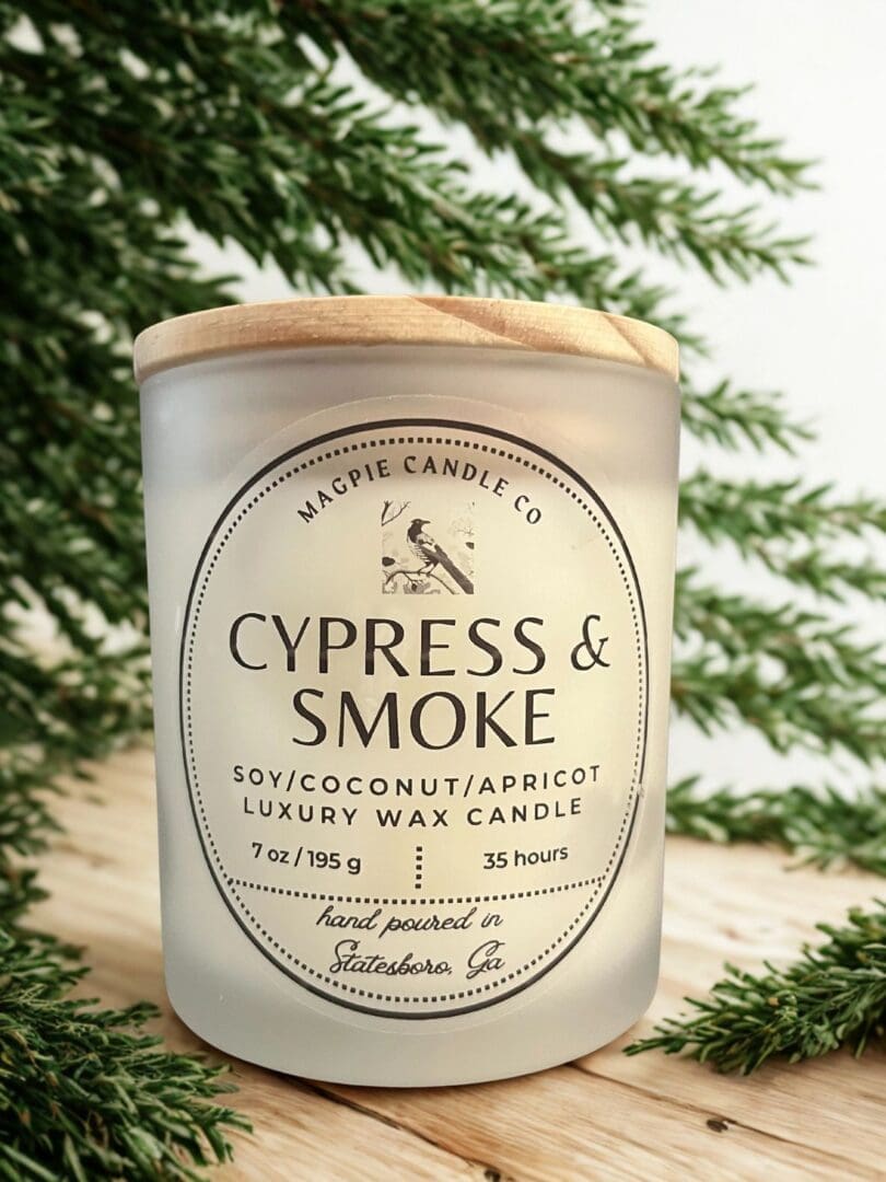 Candle labeled "Cypress & Smoke" with greenery.