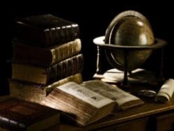 Old books and globe on wooden table.