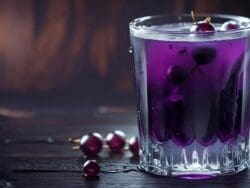 Glass of purple grape juice with grapes.