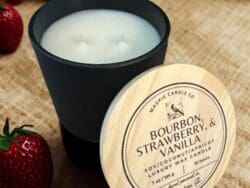 Candle with strawberries on burlap background.