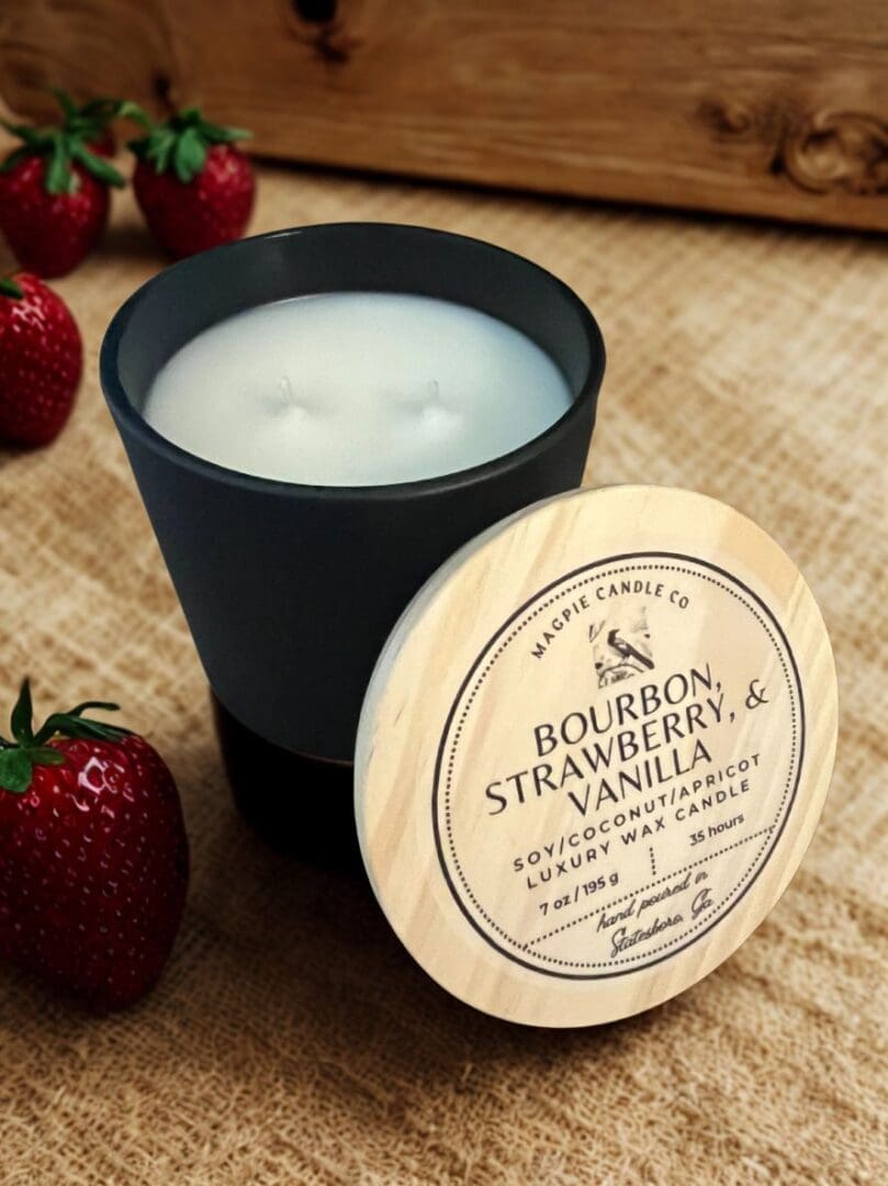 Candle with strawberries on burlap background.