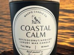 Candle labeled "Coastal Calm" with ocean sunset.